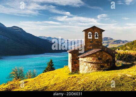 Sunny picturesque view of stone chapel on Roselend lake (Lac de Roselend) in France Alps (Auvergne-Rhone-Alpes). Landscape photography Stock Photo