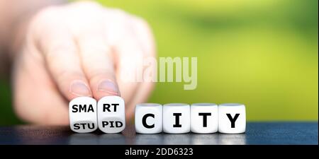 Hand turns dice and changes the expression "stupid city" to "smart city". Stock Photo