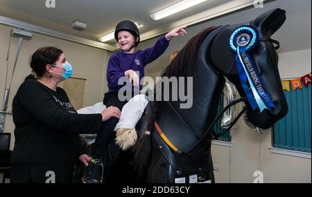 East Lothian, Scotland, UK, NHS Lothian & Muirfield Riding Therapy celebrates 10 years of Hippotherapy:  Physiotherapist Heather Falconer pioneered The Children’s Therapeutic Riding Service providing therapeutic riding free of charge to children, young people and adults with disabilities. The service was the first in Scotland for children with mobility, balance, muscle tone and coordination problems. Oreo, a mechanical horse, allows youngsters to have fun physiotherapy. Kyle Clark, aged 8 years, rides the Racewood mechanical horse simulator Stock Photo