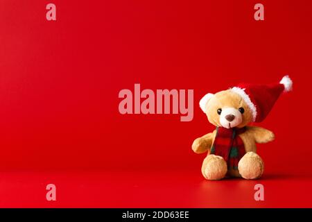 A toy bear in a red hat and scarf sits on a red background Stock Photo