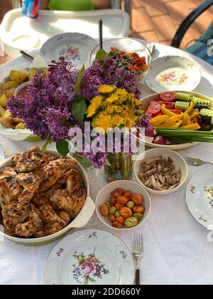 Lilac flowers with roasted chicken and salad Stock Photo