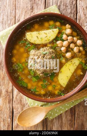 Kufta Bozbash is a traditional Azerbaijan dish, pea soup with lamb balls and vegetables close-up in a plate on the table. Vertical top view from above Stock Photo