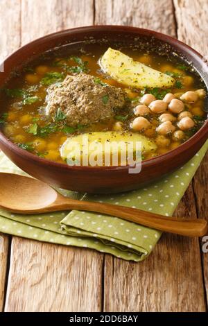 Homemade Kufta bozbash is a traditional Azerbaijani meatball soup and chickpea close-up in a plate on the table. Vertical Stock Photo