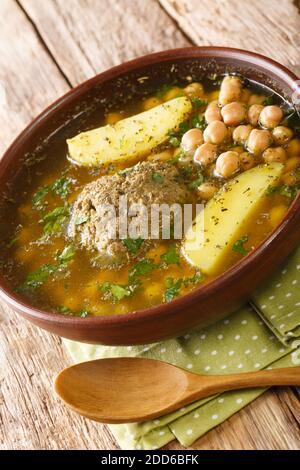 Kufta Bozbash is a traditional Azerbaijan dish, pea soup with lamb balls and vegetables close-up in a plate on the table. Vertical Stock Photo