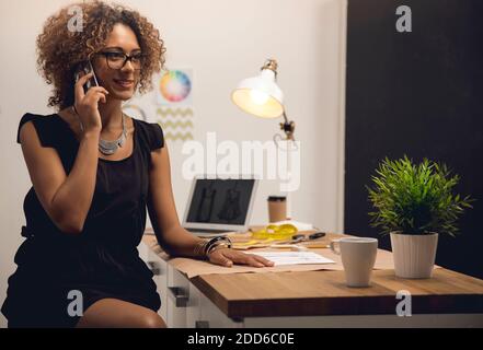 A young fashion designer on her atelier making a phone call Stock Photo