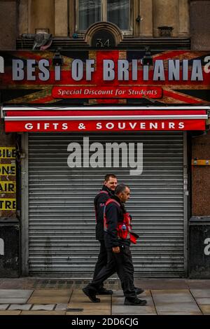 London, UK. 24th Nov, 2020. West end security patrol past a closed Best of Britania shop near Leicester square - Closed retailers do their best to promote Black Friday and Christmas sales. People are still out in central london, despite the new lockdown which is now in force. The Christmas lights are on but the shops are shut. Many people wear masks, even outside. Credit: Guy Bell/Alamy Live News Stock Photo