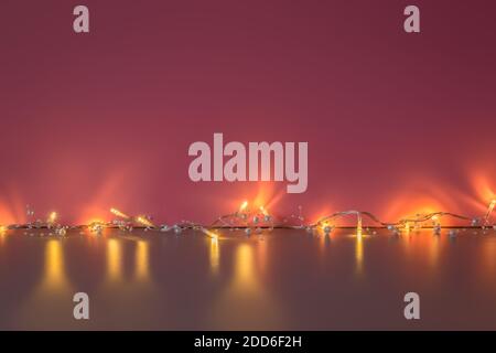 Christmas garland lights on dark pink and golden background. Garland of shining light bulbs for Christmas mockup with copy space. Christmas mood Stock Photo