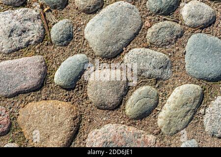 Fragment of a footpath lined with cobblestones and large stones with sand between them. For use as abstract backgrounds and textures. Stock Photo