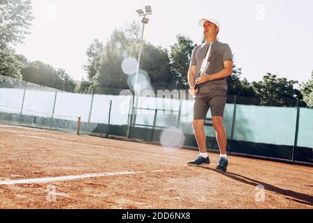 Middle-aged man playing tennis on outdoor tennis filed Stock Photo