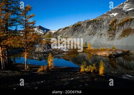 WA18500-00...WASHINGTON - The blue hour with stars in the sky reflecting in still waters of Lower Ice Lake as the full moon rises in the Glacier Peak Stock Photo