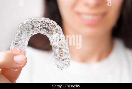 Close up orthodontic transparent aligner in womans hand. Removable braces. Stock Photo