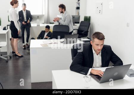 One Manager in a strict dress code works while the others rest in the chill-out zone of the open space office. Workaholic concept Stock Photo