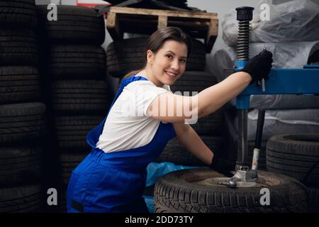 Female mechanic is using a press and looking at the camera Stock Photo