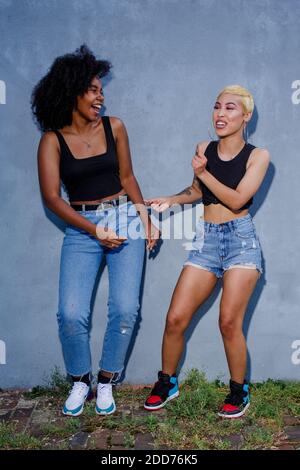 Two laughing friends in matching clothes dance together outside Stock Photo