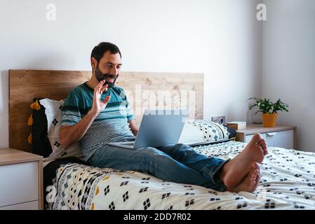 Young man lying on bed having a video call Stock Photo