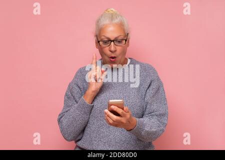 Portrait of serious senior woman using smartphone, reading or typing important message, chatting in social network Stock Photo