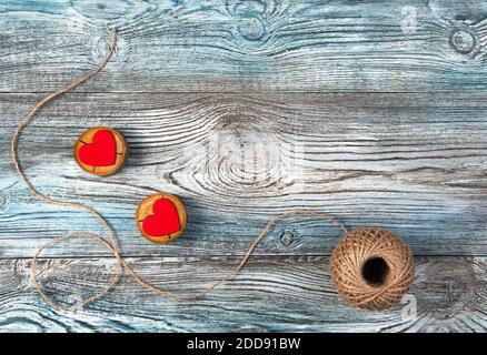 Two red hearts on wooden stands with jute thread on a wooden gray-blue background. Stock Photo
