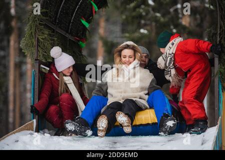 Winter entertainment for the whole family - roller coaster ride, mom, dad, daughter, son are happy and enjoy spending time together. Stock Photo