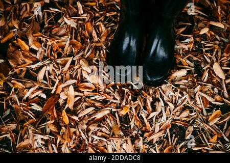 Girl wearing jump boot standing on dry leaf outdoors Stock Photo