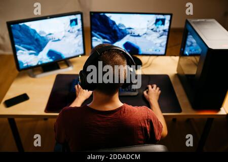 Young man playing video games with computer at desk Stock Photo