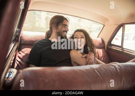Young couple laughing while relaxing in car on sunny day Stock Photo