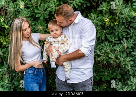 Father holding baby boy while standing by mother at park Stock Photo
