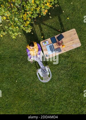 Woman drinking coffee while working on laptop at garden Stock Photo