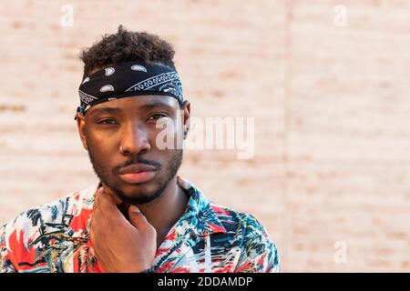 Confident young man wearing headscarf against wall Stock Photo