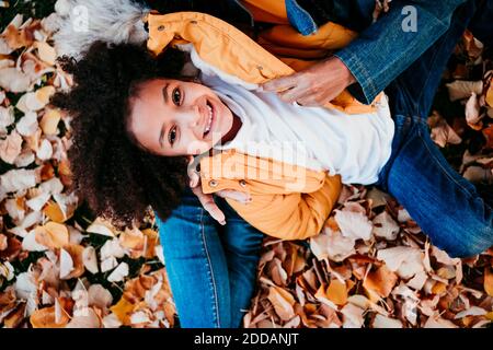 Girl smiling while lying on mother lap at park Stock Photo