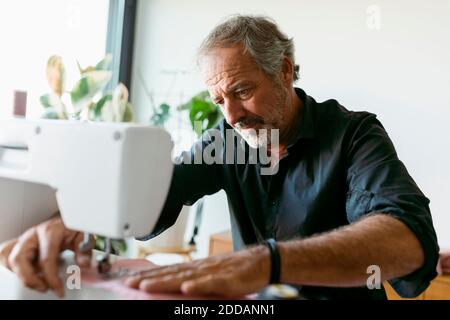 Male costume designer using sewing machine while working in studio Stock Photo