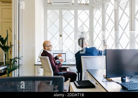 Businessmen looking at smart phone in office Stock Photo