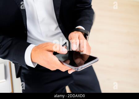 Midsection of young male entrepreneur using smart phone at creative workplace Stock Photo
