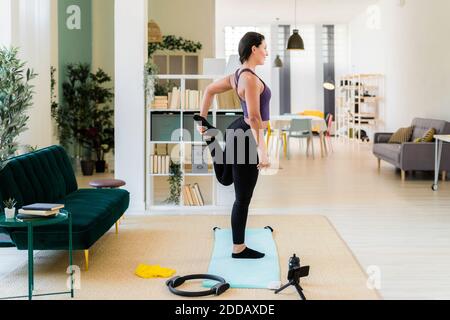 Young woman standing on one leg video recording while standing at home Stock Photo