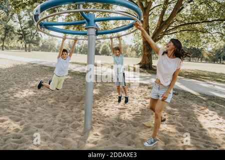Mother playing with sons in public park on sunny day Stock Photo