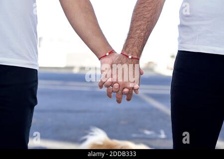 Gay couple holding hands while standing on footpath Stock Photo