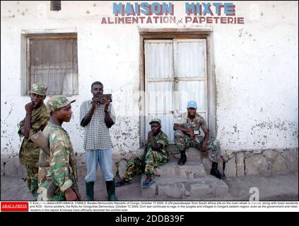 NO FILM, NO VIDEO, NO TV, NO DOCUMENTARY - © Evelyn Hockstein/KRT/ABACA. 51859-3. Baraka-Democratic Republic of Congo, October 17 2003. A UN peacekeeper from South Africa sits on the main street in Baraka along with town residents and RCD - Goma soldiers, the Rally for Congolese Democracy, October Stock Photo