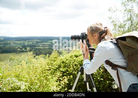 Active senior woman taking picture with camera of nature on sunny day Stock Photo