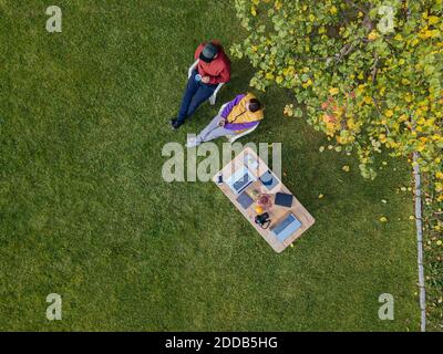 MId adult man and woman relaxing while sitting on chair by table at garden Stock Photo