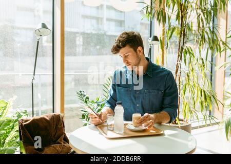 Handsome businessman using smart phone at table in cafe Stock Photo