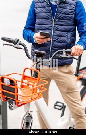 Young man using smart phone while standing with bicycle Stock Photo