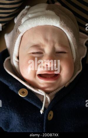Baby girl crying while lying down in house Stock Photo