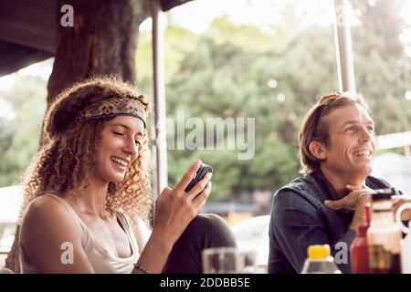 Young woman text messaging on smart phone while sitting with man in cafe Stock Photo