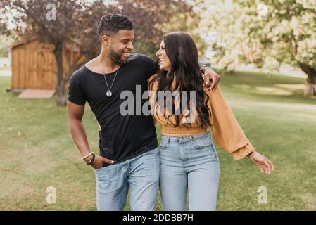 Smiling couple looking at each other while walking at backyard Stock Photo