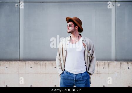 Confident man in hat looking away while standing against wall Stock Photo