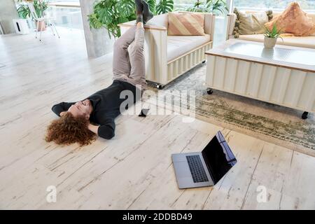 Long hair man lying down on floor in living room at home Stock Photo