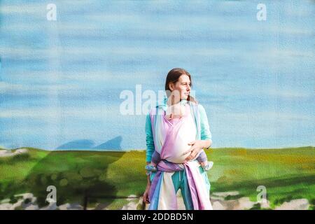 Mother carrying baby wrapped in blanket looking away while standing against wall Stock Photo