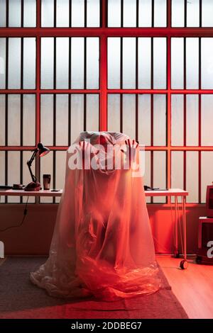 Young woman covered with plastic at home office during COVID-19 crisis Stock Photo
