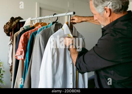 Tailor measuring shirt with tape measure at workplace Stock Photo