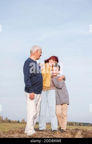 Grandmother embracing grandson while standing on haystack Stock Photo