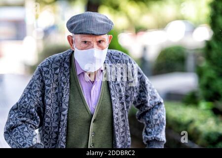 Senior man wearing protective face mask standing outdoors during COVID-19 Stock Photo